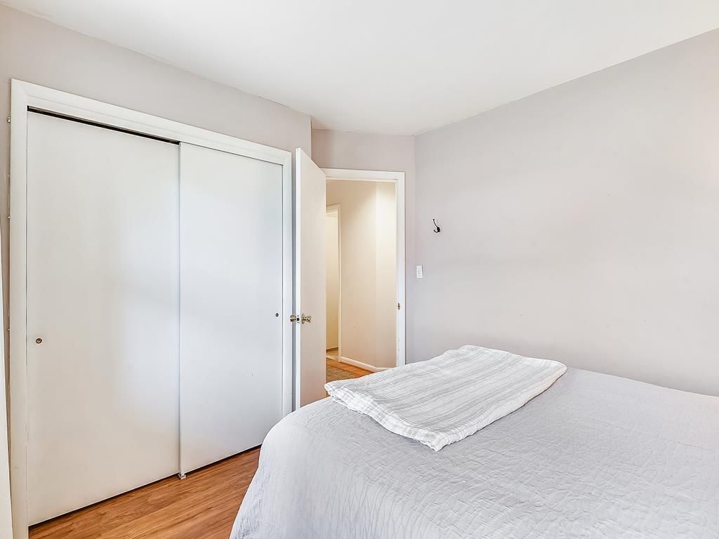 A bedroom with a bed, a wardrobe, and a door leading to another room.