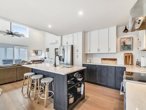Eine moderne Küche mit Kochinsel, Barhocker, Kühlschrank und Essbereich.