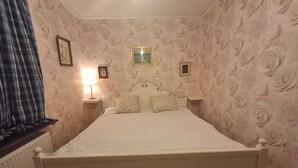 A bedroom with a large bed, floral wallpaper, two bedside tables, and a window with curtains. - Hassela Ski Vacation Home in Sweden near the lake and ski slopes (Gävleborgs)