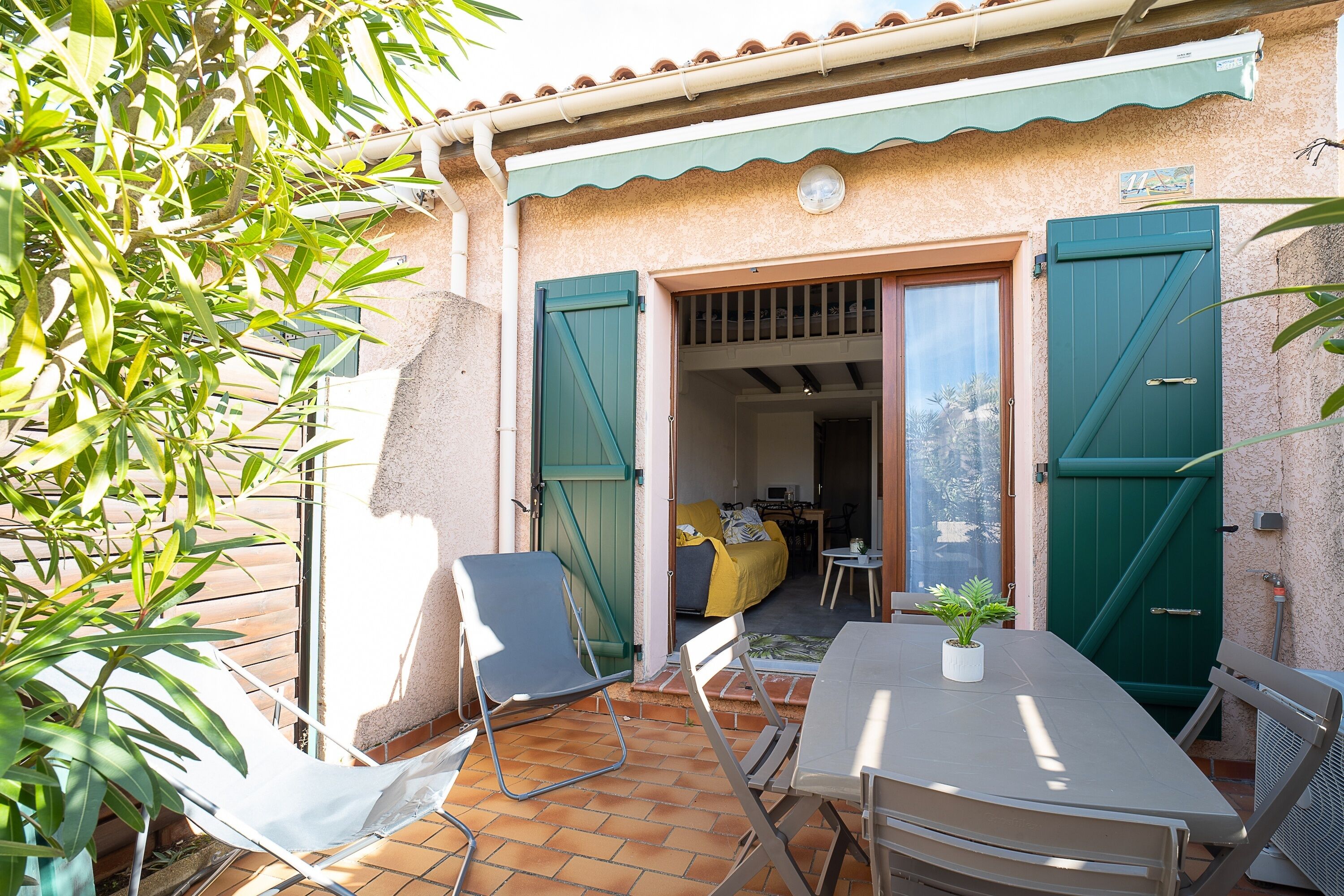 An outdoor patio with a table and chairs, a green door, and a view into the interior.