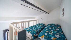 Ett sovrum med två sängar, en trappa och ett vitt tak.