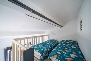 Une chambre avec deux lits, un escalier et un plafond blanc.