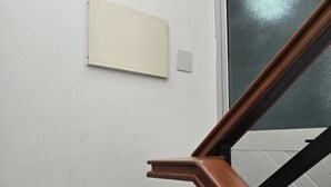 A staircase with wooden handrails and a white wall with a light switch and a small, whiteboard-like object. - Lovely 3-bedroom apartment with AC in vibrant Luanda (Luanda)