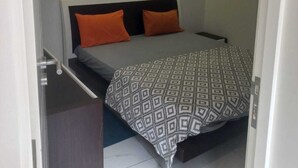 A small, neatly arranged bedroom with a bed, two pillows, a bedside table, and a patterned bedspread. - Lovely 3-bedroom apartment with AC in vibrant Luanda (Luanda)