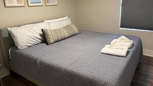 Ein ordentlich bezogenes Bett mit einem gestreiften Bettbezug, zwei Kissen und einem gefalteten Handtuch daneben.