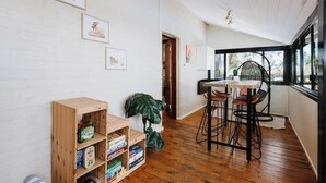 Une pièce chaleureuse avec une bibliothèque en bois, une table à manger entourée de chaises et une grande fenêtre donnant sur l’extérieur.