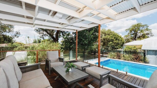 Un espace extérieur abrité, aménagé avec une piscine, une terrasse en bois et des murs en verre.