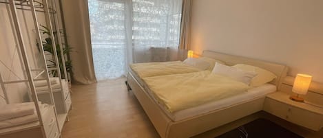 A bedroom with a bed, bedside tables, a wardrobe, and a window with curtains.