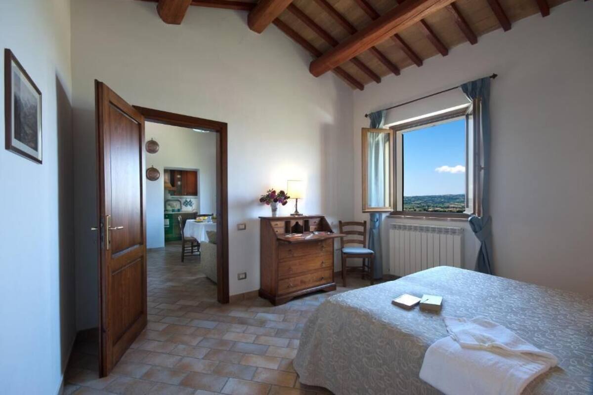 Un dormitorio con cama, cómoda, ventana con vistas y puerta que conduce a otra habitación.