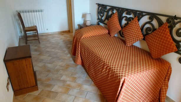 Un dormitorio con cama, una silla, una mesita de noche y un radiador.