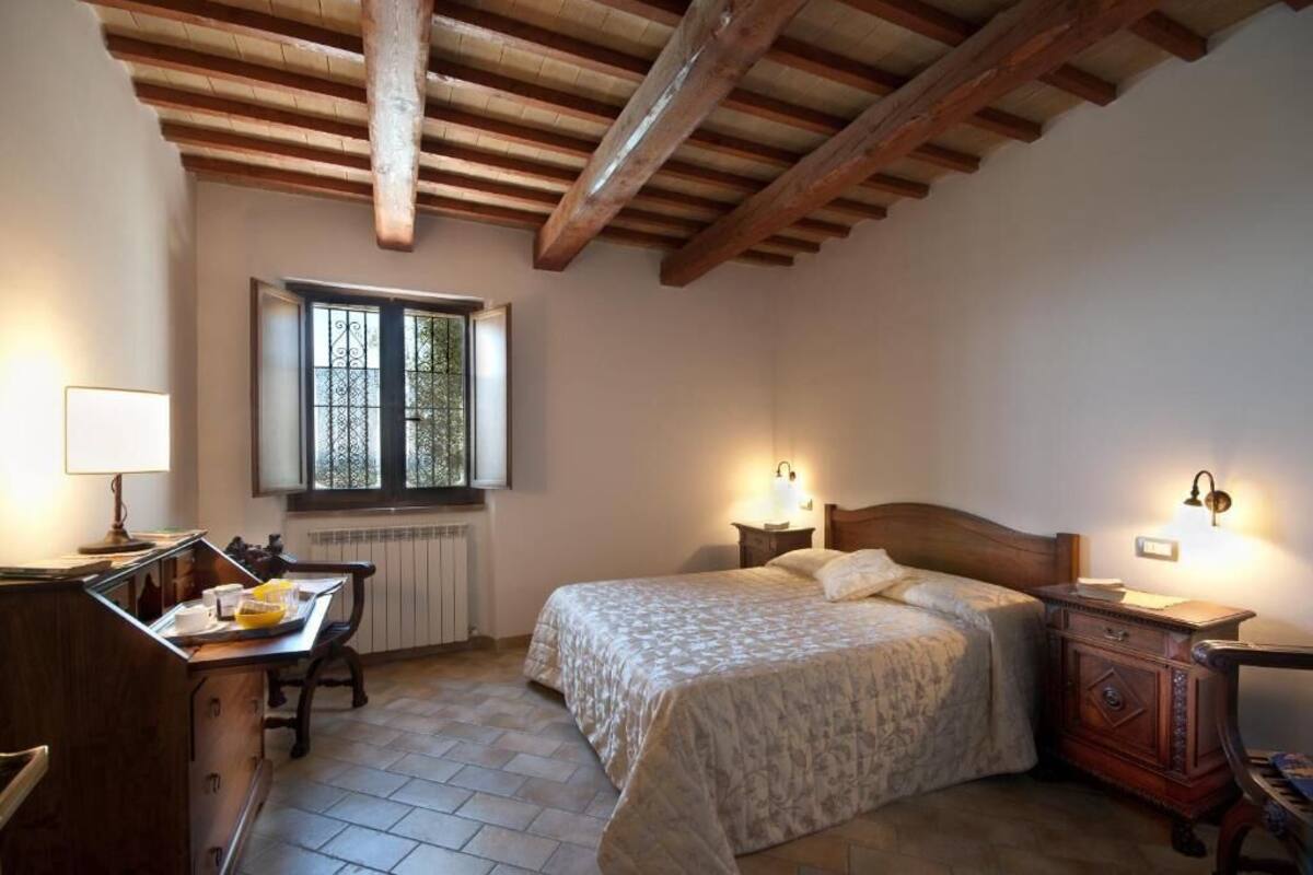 Un dormitorio con cama, mesitas de noche, un escritorio y una ventana.