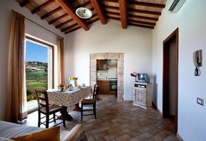 A room with a dining area, a kitchen, and a view of the countryside. - Agriturismo Fiordaliso (Trevi)