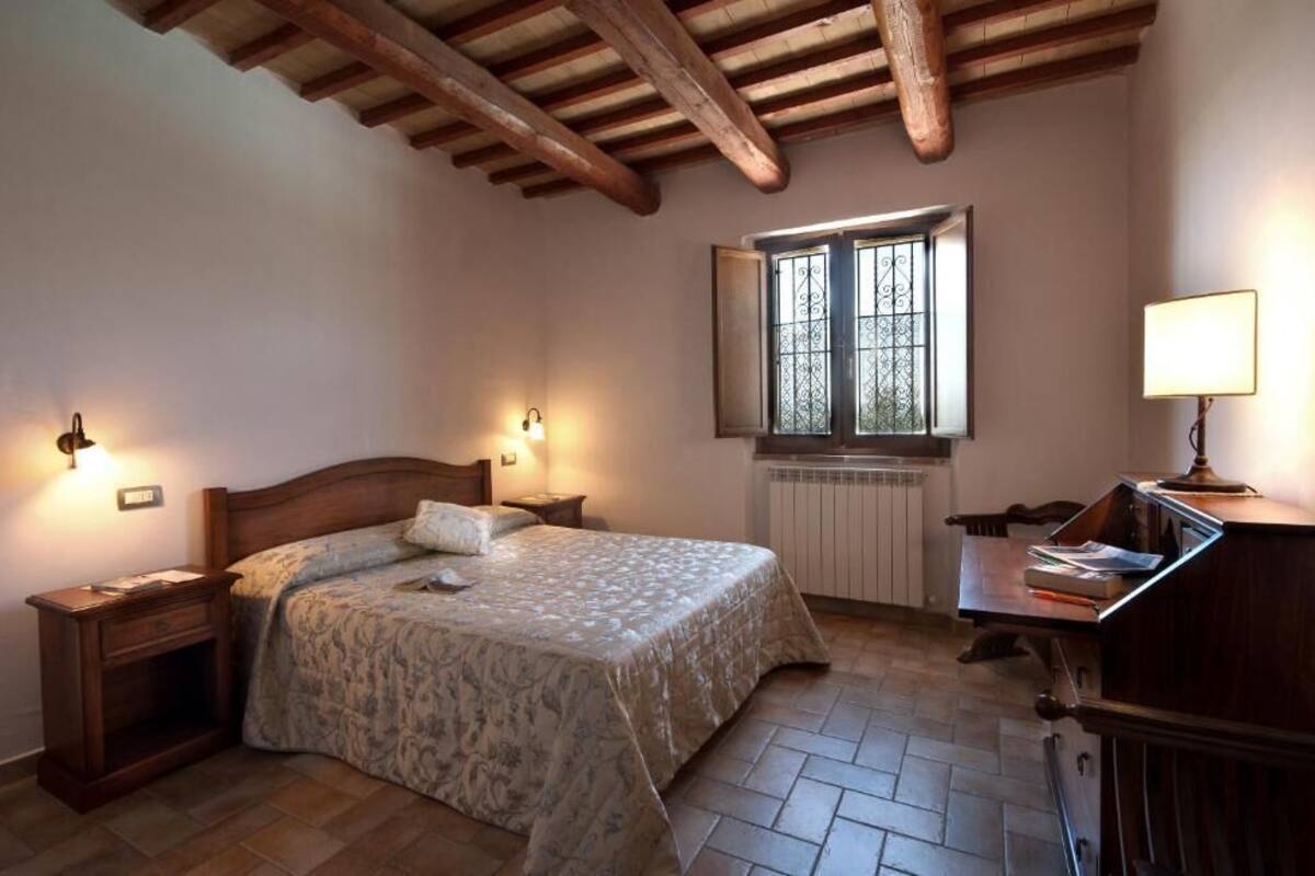 Un dormitorio con cama de madera, lámparas de noche, un escritorio y una ventana con barrotes.