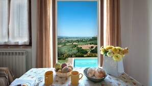 Una mesa con vistas al paisaje, un florero con flores y un cuenco de pan.