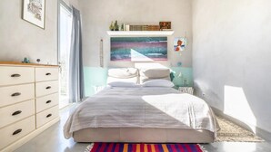 Ein Schlafzimmer mit Bett, Schminktisch, Fenster und einem Bild an der Wand.