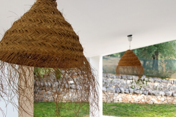 A room with a woven hanging light fixture and a stone wall.