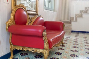 A red leather armchair with gold trim, positioned in a room with patterned floor tiles and a staircase in the background. - Villa 'La Mansarda Di Cecè' with Shared Pool, Wi-Fi and Air Conditioning (Ostuni)
