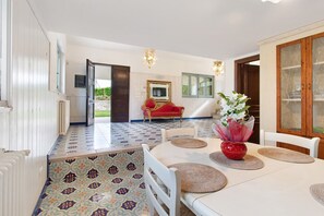 A dining area with a white table, red vase, and patterned floor tiles. - Villa 'La Mansarda Di Cecè' with Shared Pool, Wi-Fi and Air Conditioning (Ostuni)