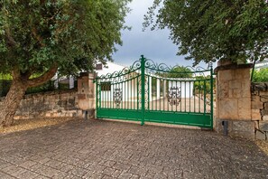 A gated entrance with a stone wall and a tree. - Villa 'La Mansarda Di Cecè' with Shared Pool, Wi-Fi and Air Conditioning (Ostuni)