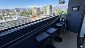A balcony with a city view, a small table, and potted plants. - Spacious apartment with panoramic view and connectivity in downtown Santiago (San Miguel)