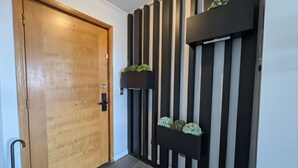 A wooden door with a modern black and white striped wall behind it, featuring two black planters with green plants. - Spacious apartment with panoramic view and connectivity in downtown Santiago (San Miguel)