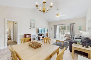 A spacious living room with a dining table, chairs, a sofa, a TV, and a chandelier. - Golf course view condo with private balcony, W/D, pool & close to beach (Myrtle Beach)