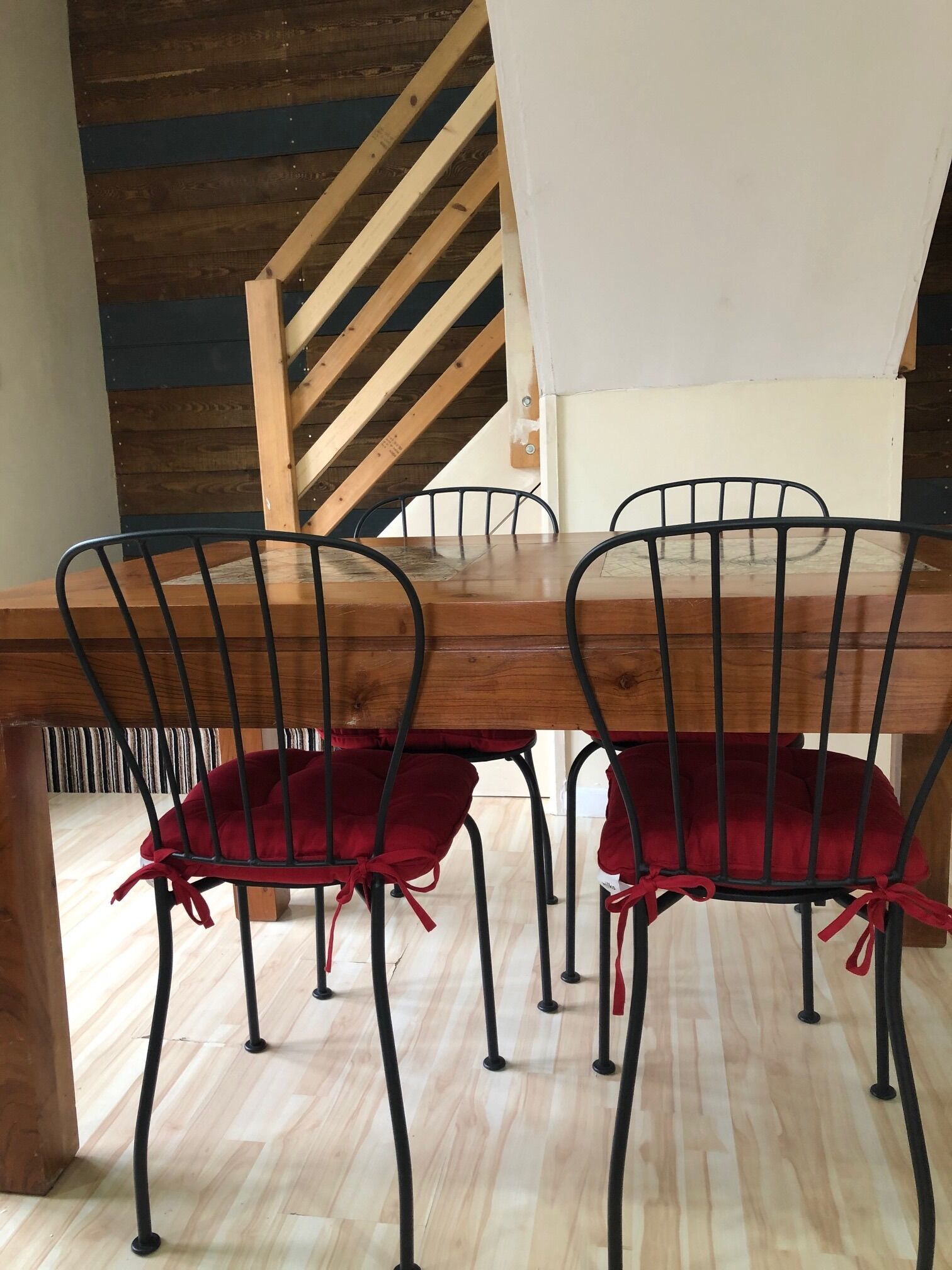 A dining area with a wooden table and metal chairs with red cushions.