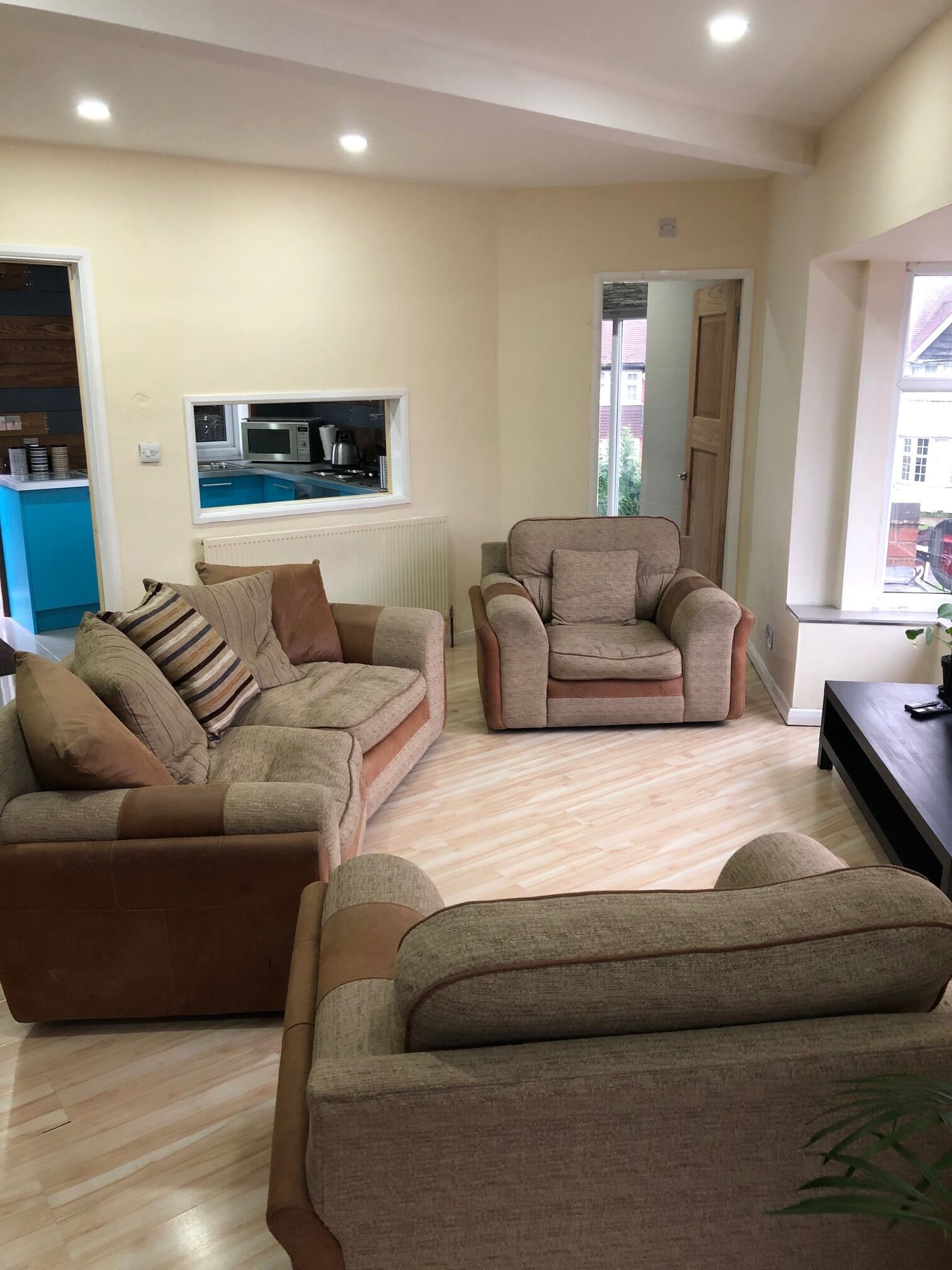 A living room with two sofas, a coffee table, and a view of a kitchen through a window.
