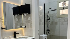 Une salle de bain moderne avec un lavabo blanc, un robinet noir et une douche séparée par des parois en verre.