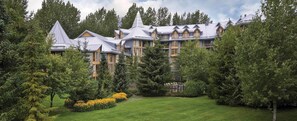 A large, multi-story building with a symmetrical facade, surrounded by lush greenery and a well-maintained lawn. - Spacious 1-bedroom condo with fire place  in enchanting Whistler (Whistler)