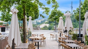 Un espace extérieur aménagé avec des tables, des chaises, des parasols et des arbres.