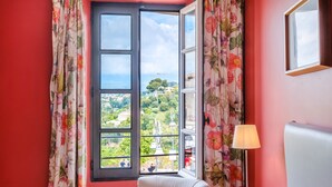 Une pièce avec une grande fenêtre, une chaise, une lampe et un miroir au mur.