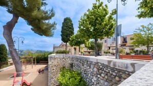 Un parc avec une aire de jeux, un mur en pierre et des bancs.