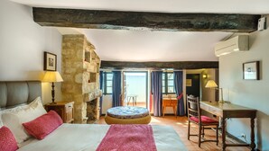 A bedroom with a bed, a desk, a chair, a lamp, and a stone wall. - Suite with Sea View, Wi-Fi and Air Conditioning (Cagnes-sur-Mer)