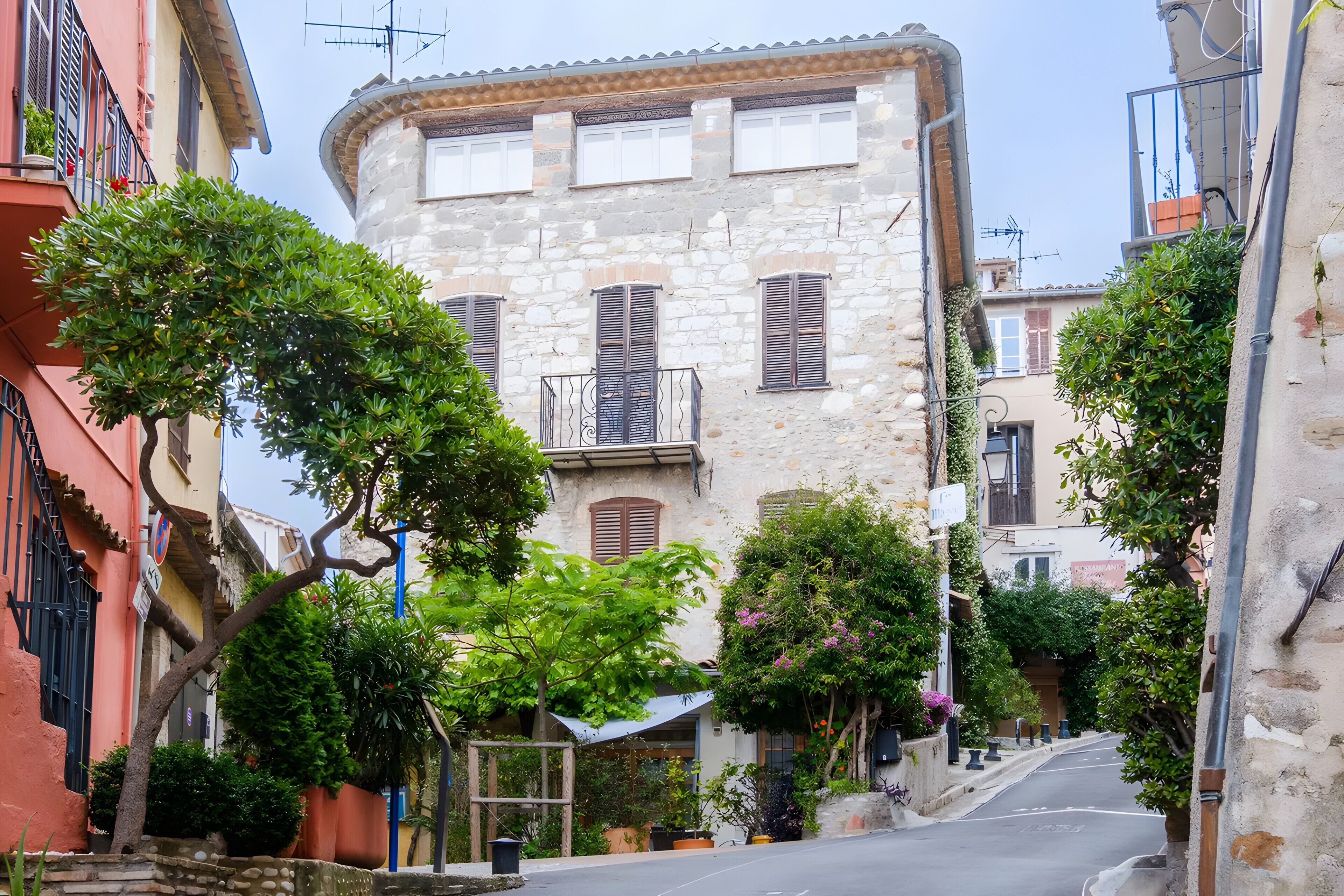 Una calle estrecha con edificios de piedra, balcones y plantas en macetas.