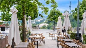 An outdoor seating area with tables and chairs, umbrellas, and trees. - Double Room with Wi-Fi and Air Conditioning (Cagnes-sur-Mer)