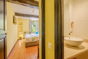 Une chambre d’hôtel avec un lit, une salle de bain dotée d’un grand lavabo et une vue sur l’extérieur.