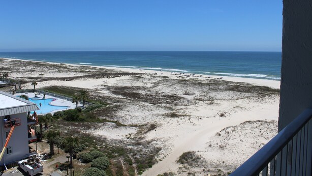 A beach view with a clear sky, a sandy beach, and a pool area. - Couples Coastal Retreat 1min walk to the beach! (Gulf Shores)