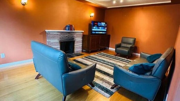 Ein Wohnzimmer mit Kamin, zwei blaue Sofas, einem Fernseher und einem Streifenmuster-Teppich.
