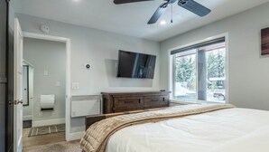 Ein Schlafzimmer mit einem Bett, einem Fernseher, einer Heizung, einem Fenster und einer Tür.