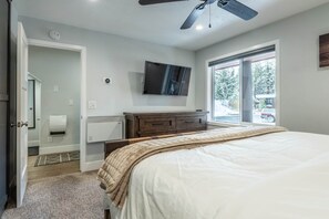 Ein Schlafzimmer mit einem Bett, einem Fernseher, einer Heizung, einem Fenster und einer Tür.