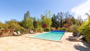 A rectangular swimming pool with a blue border, surrounded by a paved patio with beige tiles. - Domaine des Bruyères | Workshop (Saint-Savin)