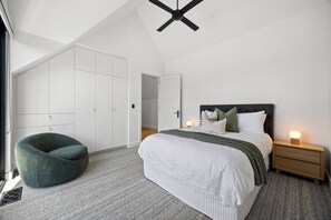 Une chambre à coucher comprenant un lit, des tables de chevet, une chaise et une armoire.
