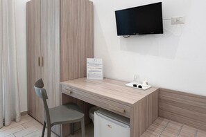 Une petite pièce comprenant un bureau en bois, une chaise, un téléviseur et un réfrigérateur.