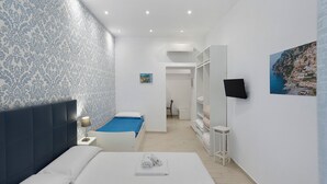 Ein Hotelzimmer mit Bett, einem kleinen Schreibtisch, einem Fernseher und einem Bild an der Wand.