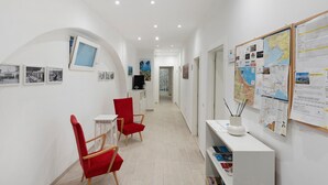 Ein Flur mit roten Stühlen, einem weißen Tisch und einer weißen Kommode mit Büchern.