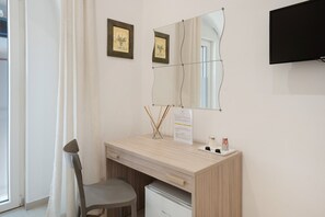 Une chambre moderne avec un bureau en bois, une chaise, un miroir et un téléviseur fixé au mur.