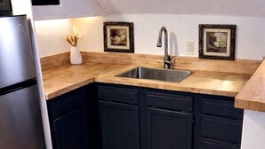 A kitchen with dark cabinets, a stainless steel refrigerator, and wooden countertops. - THE GEORGIA ROSE - A southern charm, with lots of character! (Atlanta)