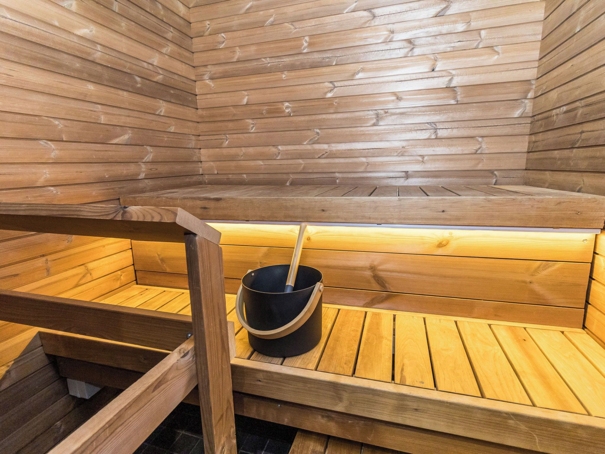 A sauna with wooden benches and a bucket.