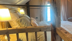 Een rustieke slaapkamer met een houten hoofdeinde, een bed met witte lakens en een bedlamp.